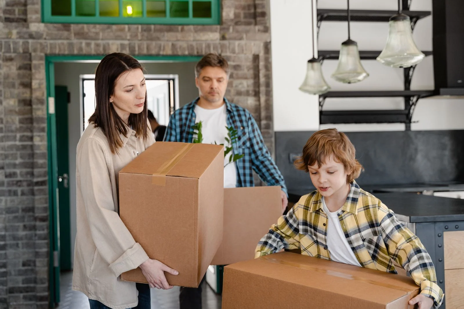 Familie trägt Umzugskartons durch die neue Wohnung.