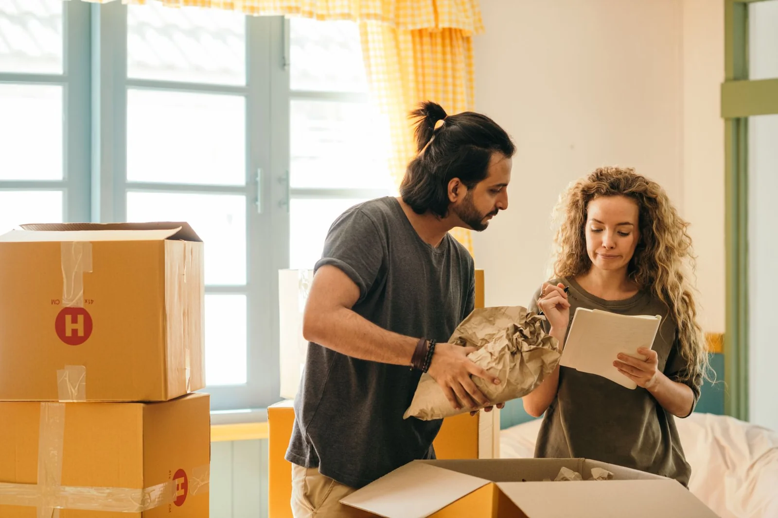 Paar prüft seine Liste zwischen gepackten Umzugskartons